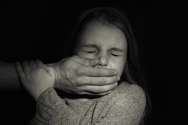 Man's,Hand,Covering,Mouth,Of,Little,Girl,On,Black,Background.